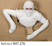 Мужчина в бинтах прорывается сквозь дыру в картоне. Стоковое фото, фотограф pzAxe / Фотобанк Лори