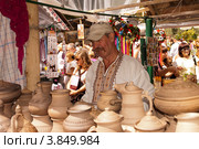 Сорочинская ярмарка. Гончар продает глиняную посуду (2012 год). Редакционное фото, фотограф Олег Голиков / Фотобанк Лори