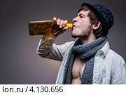 Модный мужчина в шляпе пьет текилу из бутылки, серый фон. Стоковое фото, фотограф Logunov Maxim / Фотобанк Лори