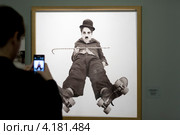 Человек снимает фотографию "Каток" на телефон на выставке "Чарли Чаплин" в Мультимедиа Арт Музее города Москвы (2013 год). Редакционное фото, фотограф Николай Винокуров / Фотобанк Лори