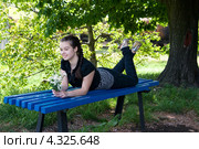 Девочка-подросток отдыхает на синей скамейке. Стоковое фото, фотограф Яна Гуляновская / Фотобанк Лори