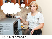 Женщина на кухне около открытой микроволновки. Стоковое фото, фотограф Кекяляйнен Андрей / Фотобанк Лори