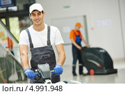 Улыбающийся молодой работник убирается в холле бизнес-центра. Стоковое фото, фотограф Дмитрий Калиновский / Фотобанк Лори
