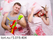 Пара в постели: муж играет на гитаре, жена накрылась подушкой. Стоковое фото, фотограф Иванов Алексей / Фотобанк Лори
