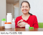 Улыбающаяся женщина средних лет пробует крем на тыльной стороне руки. Стоковое фото, фотограф Яков Филимонов / Фотобанк Лори