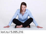Сосредоточенная девушка сидит на полу, скрестив ноги и глядя исподлобья. Стоковое фото, фотограф Phovoir Images / Фотобанк Лори