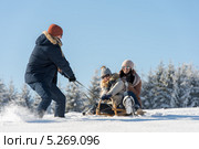 Молодой человек катает своих подруг на деревянных санях. Стоковое фото, фотограф CandyBox Images / Фотобанк Лори