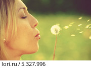 Девушка сдувает семена одуванчика на фоне зеленой травы. Стоковое фото, фотограф Raev Denis / Фотобанк Лори