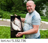 Мужчина держит коптилку с двумя лещами (2013 год). Редакционное фото, фотограф Игорь Низов / Фотобанк Лори
