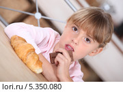 Девочка за столом с круассаном и шоколадкой. Стоковое фото, фотограф Phovoir Images / Фотобанк Лори