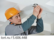 Электрик монтирует точечный светильник в потолок. Стоковое фото, фотограф Дмитрий Калиновский / Фотобанк Лори