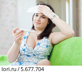 Женщина прикладывает полотенце ко лбу и смотрит на градусник. Стоковое фото, фотограф Яков Филимонов / Фотобанк Лори