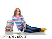 Юная студентка читает книгу, полулежа на полу рядом с высокой стопкой книг, на белом фоне. Стоковое фото, фотограф Elnur / Фотобанк Лори