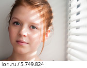 Рыжеволосая девочка-подросток возле окна закрытыми жалюзи. Стоковое фото, фотограф Игорь Низов / Фотобанк Лори