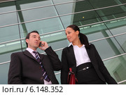 Pair of execs using a cellphone outside an office building. Стоковое фото, фотограф Phovoir Images / Фотобанк Лори
