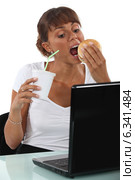 Woman eating at her desk. Стоковое фото, фотограф Phovoir Images / Фотобанк Лори