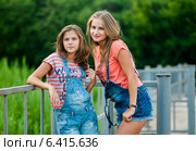 Две девушки в джинсовых шортах стоят возле железного забора. Стоковое фото, фотограф Игорь Низов / Фотобанк Лори