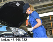 Женщина-сборщик крепит деталь в подкапотном пространстве автомобиля. Сборочный цех автомобильного предприятия (2014 год). Редакционное фото, фотограф Ирина Борсученко / Фотобанк Лори