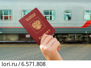 Российский паспорт в руке на фоне железнодорожного вагона. Электронный билет на поезд. Стоковое фото, фотограф Володина Ольга / Фотобанк Лори