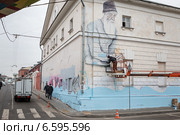 Угол дома и человек, наносящий граффити (2014 год). Редакционное фото, фотограф Родион Власов / Фотобанк Лори