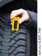 woman measures tire tread of a car tire. Стоковое фото, фотограф Erwin Wodicka / Фотобанк Лори