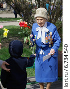 Ребенок дарит цветы труженице  тыла военных лет (2014 год). Редакционное фото, фотограф Ольга Вьюшкова / Фотобанк Лори