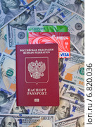Заграничный паспорт гражданина Российской Федерации с вложенными банковскими картами на фоне 100-долларовых купюр (2014 год). Редакционное фото, фотограф Александр Тарасенков / Фотобанк Лори