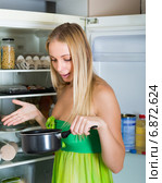 Woman holding foul food near fridge. Стоковое фото, фотограф Яков Филимонов / Фотобанк Лори