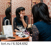 Женщина средних лет красит лицо кисточкой сидя перед комодом. Стоковое фото, фотограф Игорь Низов / Фотобанк Лори