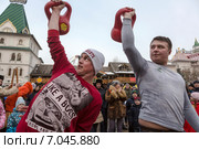 Мужчины состязаются в подъеме гири во время масленичных потех на фоне терема в Измайловском кремле в праздник Широкой Масленицы, Москва (2015 год). Редакционное фото, фотограф Николай Винокуров / Фотобанк Лори