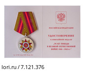 Юбилейная медаль «70 лет Победы в Великой Отечественной войне 1941—1945 гг.» и удостоверение к ней на белом фоне (2015 год). Редакционное фото, фотограф Владимир Сергеев / Фотобанк Лори