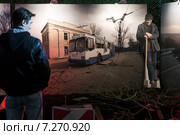 Посетитель смотрит на фотографию из зоны боевых действий на Донбассе, установленную в павильоне "Украина" на ВДНХ во время выставки "Вещественные доказательства. Донбасс. 365 дней" в городе Москве, Россия (2015 год). Редакционное фото, фотограф Николай Винокуров / Фотобанк Лори