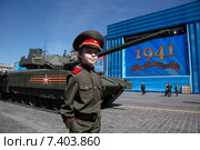 Мальчик в военной форме стоит у танка Т-14 на гусеничной платформе "Армата", который остановился на Красной площади во время генеральной репетиции военного парада в ознаменование 70-летия Победы в Великой Отечественной войне в городе Москве, Россия (2015 год). Редакционное фото, фотограф Николай Винокуров / Фотобанк Лори