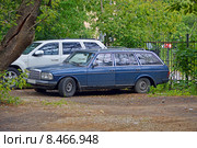 Старая иномарка-универсал (Mercedes Benz S123) синего цвета, стоящая около ограды во дворе дома днем (2015 год). Редакционное фото, фотограф Александр Замараев / Фотобанк Лори