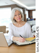 Senior woman at home writing on agenda. Стоковое фото, фотограф Fabrice Michaudeau / PantherMedia / Фотобанк Лори