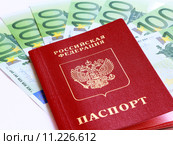 Заграничный паспорт гражданина Российской Федерации лежит на нескольких купюрах в сто евро. Стоковое фото, фотограф Артём Крылов / Фотобанк Лори