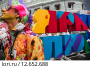 Артист театральной группы "Огненные люди" стоит у надписи "Яркие люди" во время карнавального шествия фестиваля на Неглинной улице в праздник День города Москвы, Россия (2015 год). Редакционное фото, фотограф Николай Винокуров / Фотобанк Лори