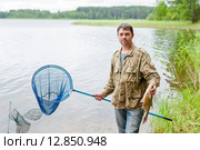 Счастливый рыбак с лещом и с сачком в руках на фоне реки. Стоковое фото, фотограф Игорь Низов / Фотобанк Лори