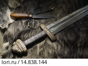 Средневековый меч викингов лежит на меху рядом с ножом и фибулой. Стоковое фото, фотограф Дмитрий Черевко / Фотобанк Лори