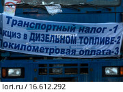 Большегрузный автомобиль с плакатом, где перечислены налоги для грузовых автомобилей, против введения платы на федеральных дорогах для грузовых перевозчиков (система "Платон") в подмосковном городе Химки, Россия (2015 год). Редакционное фото, фотограф Николай Винокуров / Фотобанк Лори