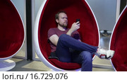 Человек пишет sms в кресле-яйцевидной формы. Стоковое видео, видеограф Валентин Беспалов / Фотобанк Лори