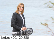 Молодая красивая девушка присела у реки в теплую осеннюю погоду. Стоковое фото, фотограф Иванов Алексей / Фотобанк Лори