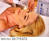 Young woman receiving electric facial massage. Стоковое фото, фотограф Gennadiy Poznyakov / Фотобанк Лори