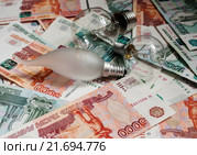 Три электрические лампочки лежат на российских банкнотах (2016 год). Редакционное фото, фотограф Игорь Низов / Фотобанк Лори