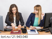 Две молодые девушки работают в офисе, одна складывает лист бумаги, вторая с удивлением смотрит на нее. Стоковое фото, фотограф Иванов Алексей / Фотобанк Лори