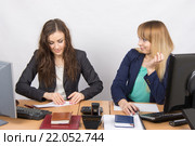 Две молодые девушки работают в офисе, одна делает бумажный самолет, вторая с ненавистью смотрит на нее. Стоковое фото, фотограф Иванов Алексей / Фотобанк Лори