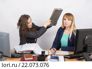 Девушка в офисе бьет по голове свою коллегу большой папкой. Стоковое фото, фотограф Иванов Алексей / Фотобанк Лори