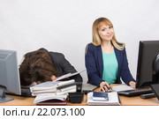 Девушки коллеги в офисе, одна уснула на куче папок, вторая работает в компьютере и посмотрела в кадр. Стоковое фото, фотограф Иванов Алексей / Фотобанк Лори