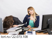 Девушки коллеги в офисе, одна уснула на куче папок, вторая показывает на нее пальцем и смотрит в кадр. Стоковое фото, фотограф Иванов Алексей / Фотобанк Лори