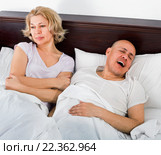 Mature tired evil girl looking at snoring boyfriend. Стоковое фото, фотограф Яков Филимонов / Фотобанк Лори